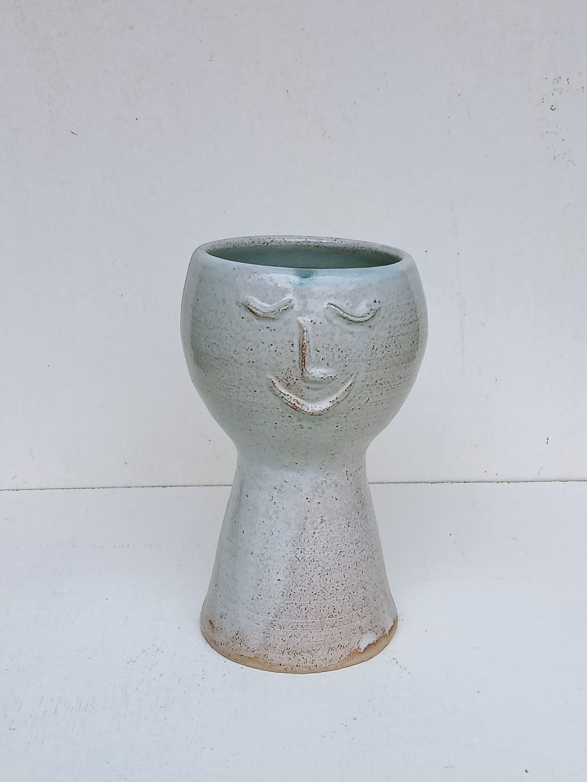 cache pot gris en terre de grès avec un visage