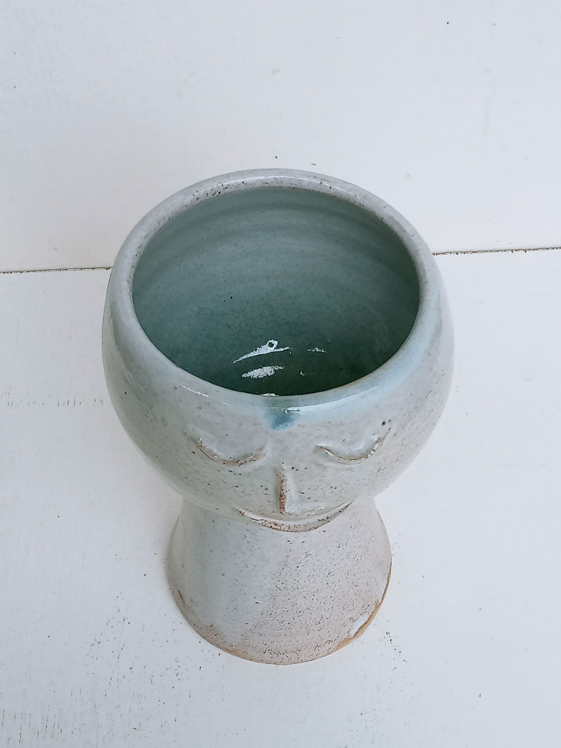 cache pot gris en terre de grès avec un visage