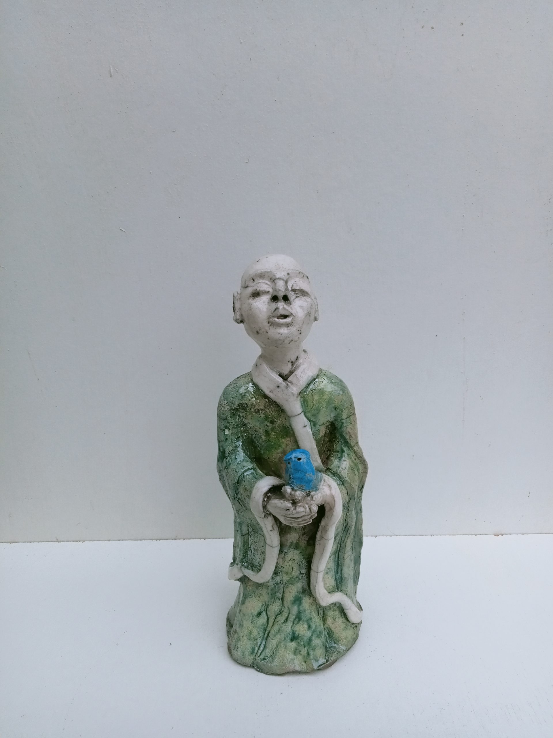 moine tibétain débout avec un oiseau bleu dans les mains